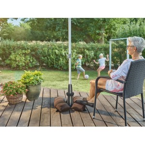 Baser Sonnenschirmständer 30 kg, dunkelgrau, mit Sandsäcken auf Holzterrasse. Im Hintergrund spielende Kinder.