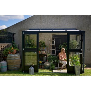 Juliana Gewächshaus Veranda 4 Anthrazit mit Frau im Inneren, Pflanzen und Gartenzubehör.