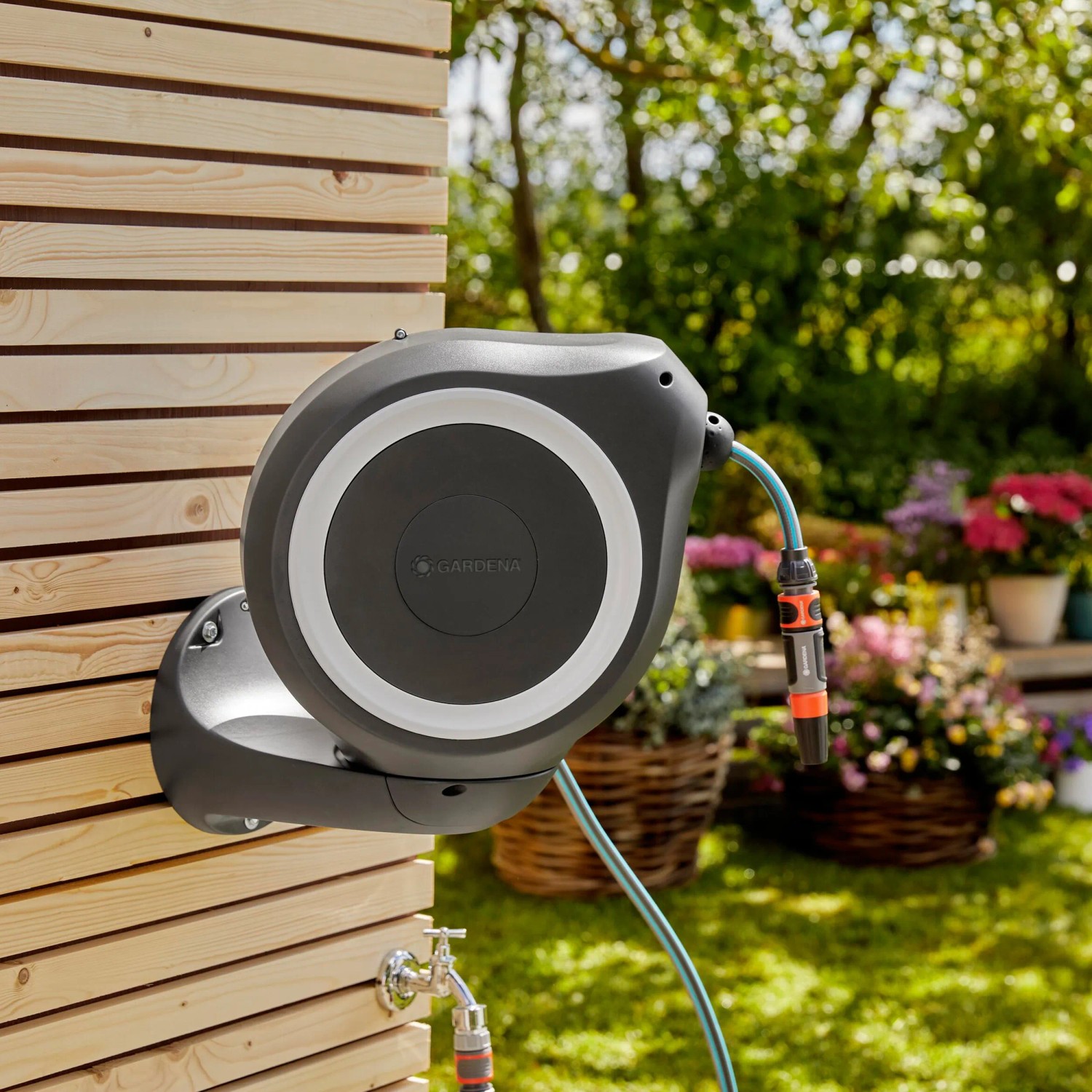 Gardena Wand-Schlauchbox RollUp S mit 15m Schlauch am Holzhaus. Gartenschlauchwagen für die Gartenbewässerung.