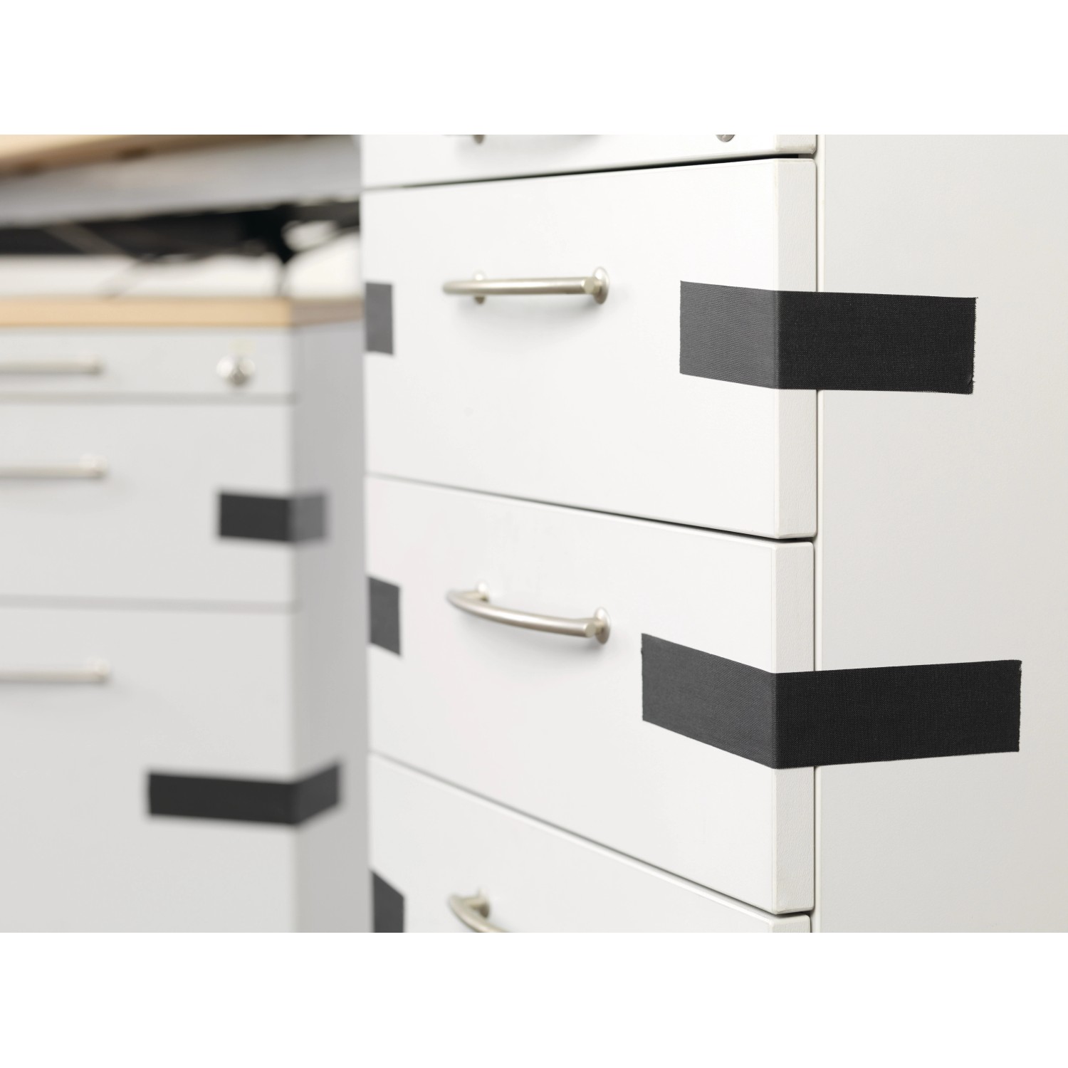 Tesa Extra Power Eco Repair, schwarzes Gewebeband zum Reparieren und Befestigen an einem weißen Schrank.