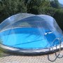 Runde, transparente Chemoform Pool-Abdeckung Cabrio Dom SH Ø 320 cm x 145 cm über einem Pool im Garten.