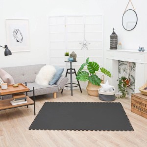 Schwarze LittleTom Baby & Kinder Puzzlematte aus 18 EVA-Schaumstoffteilen auf hellem Holzboden im Wohnzimmer.