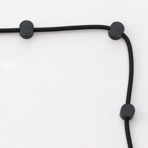 Orion Lightstyle Kabelhalter aus schwarzem Kunststoff fixieren ein schwarzes Textilkabel an einer weißen Wand. Saubere Kabelführung für Lampen & Leuchten.