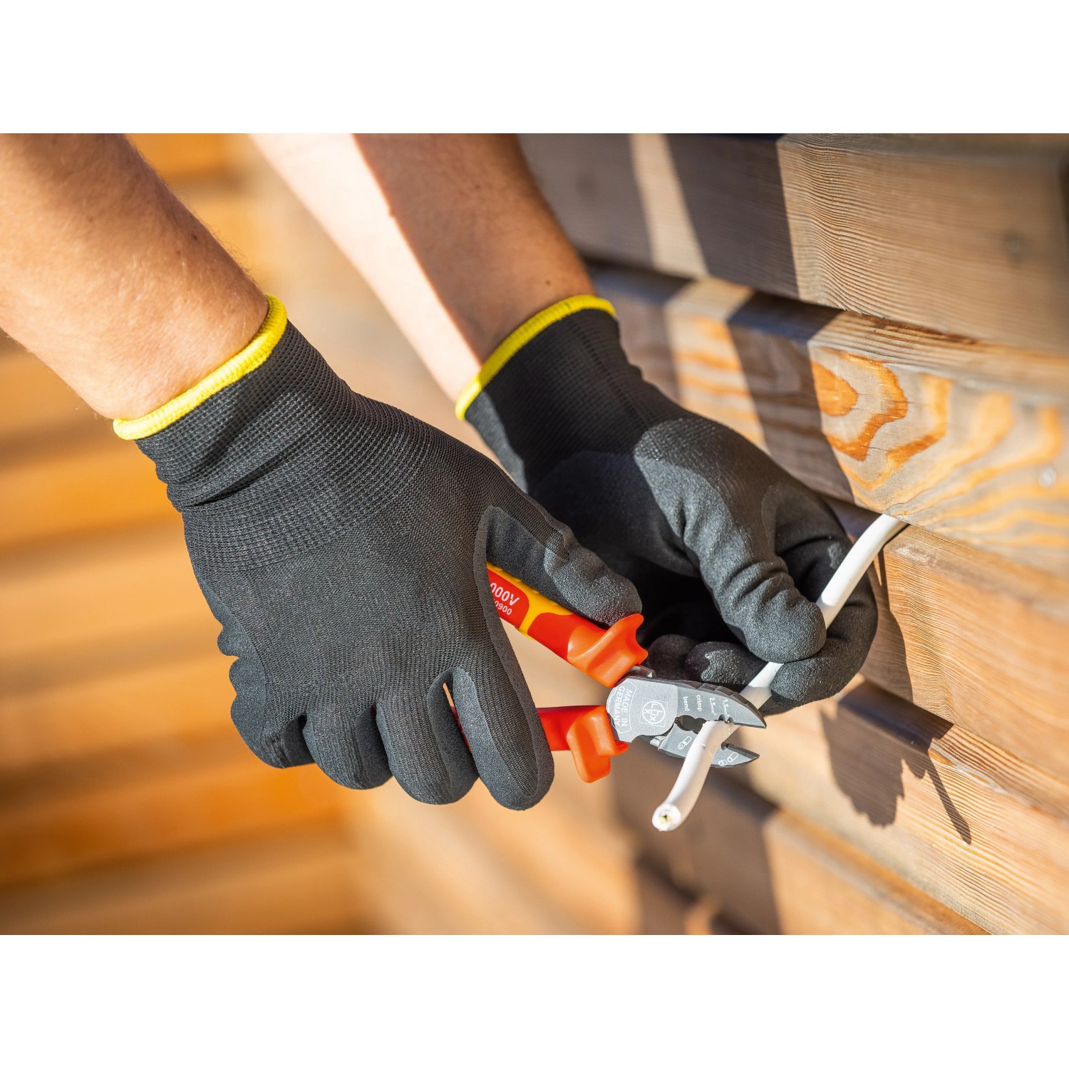 Hände mit LUX Arbeitshandschuhen Green Glove Gr. 9 schneiden Kabel mit einer Zange.