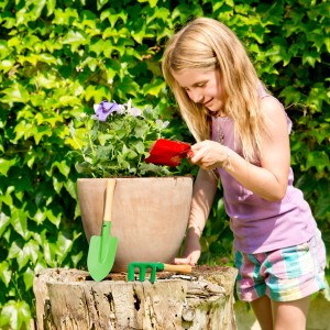 Mädchen gießt Blumen mit Kinder-Gartenwerkzeug-Set (3-teilig) im Garten.