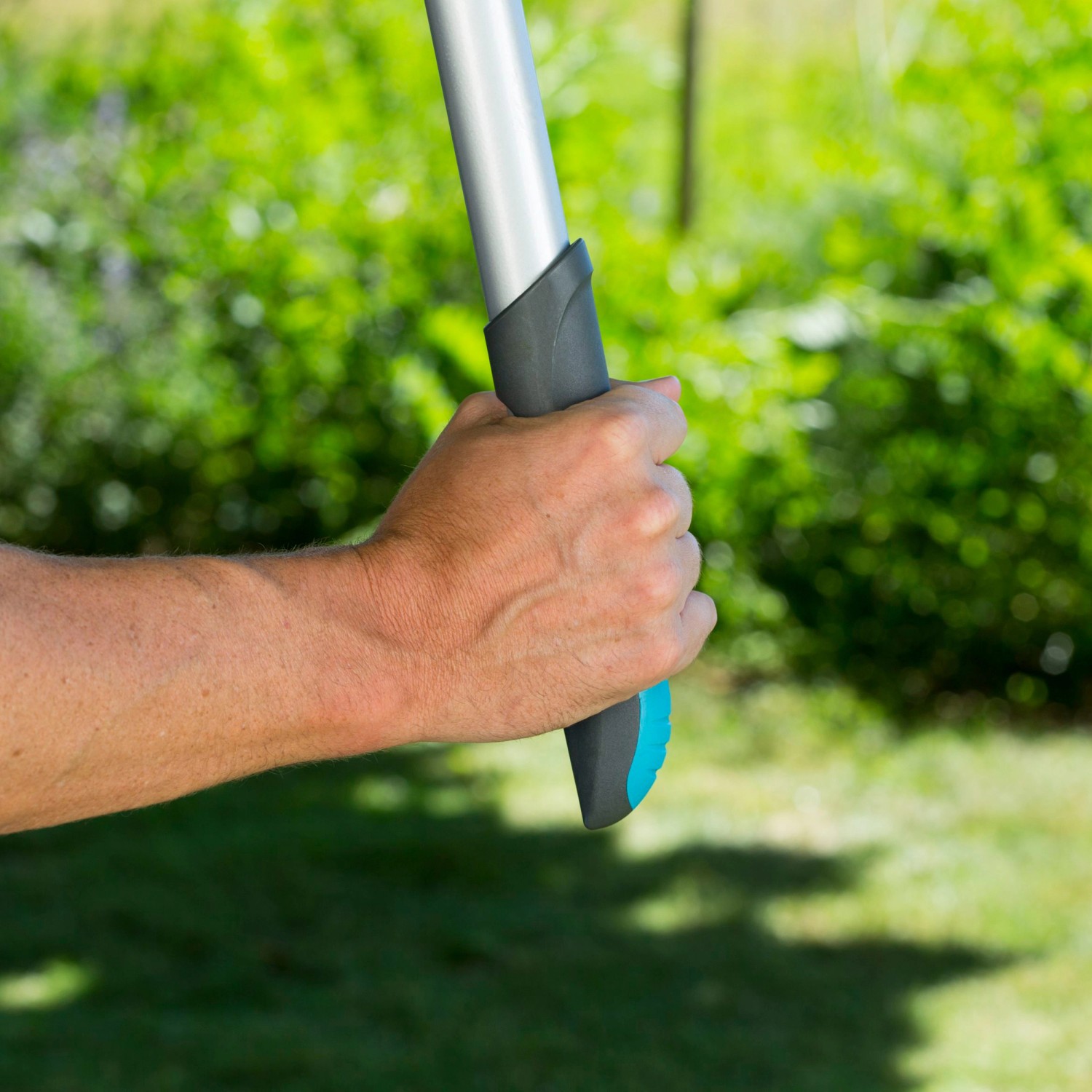 Hand hält Gardena Comfort Ratschen-Astschere SmartCut mit Soft-Griff im Garten.