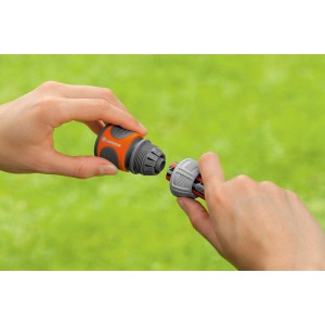 Gardena Schlauchverbinder (13 mm/15 mm) in Aktion: Zwei Hände verbinden die Kupplung vor grünem Hintergrund.