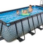 Rechteckiger, grauer EXIT Stone Pool 540x250x122cm mit Steinmuster, Leiter und Sandfilterpumpe. Personen im Pool.