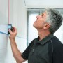 Handwerker misst mit Bosch Professional Laser-Entfernungsmesser GLM 40 digital eine Wand.