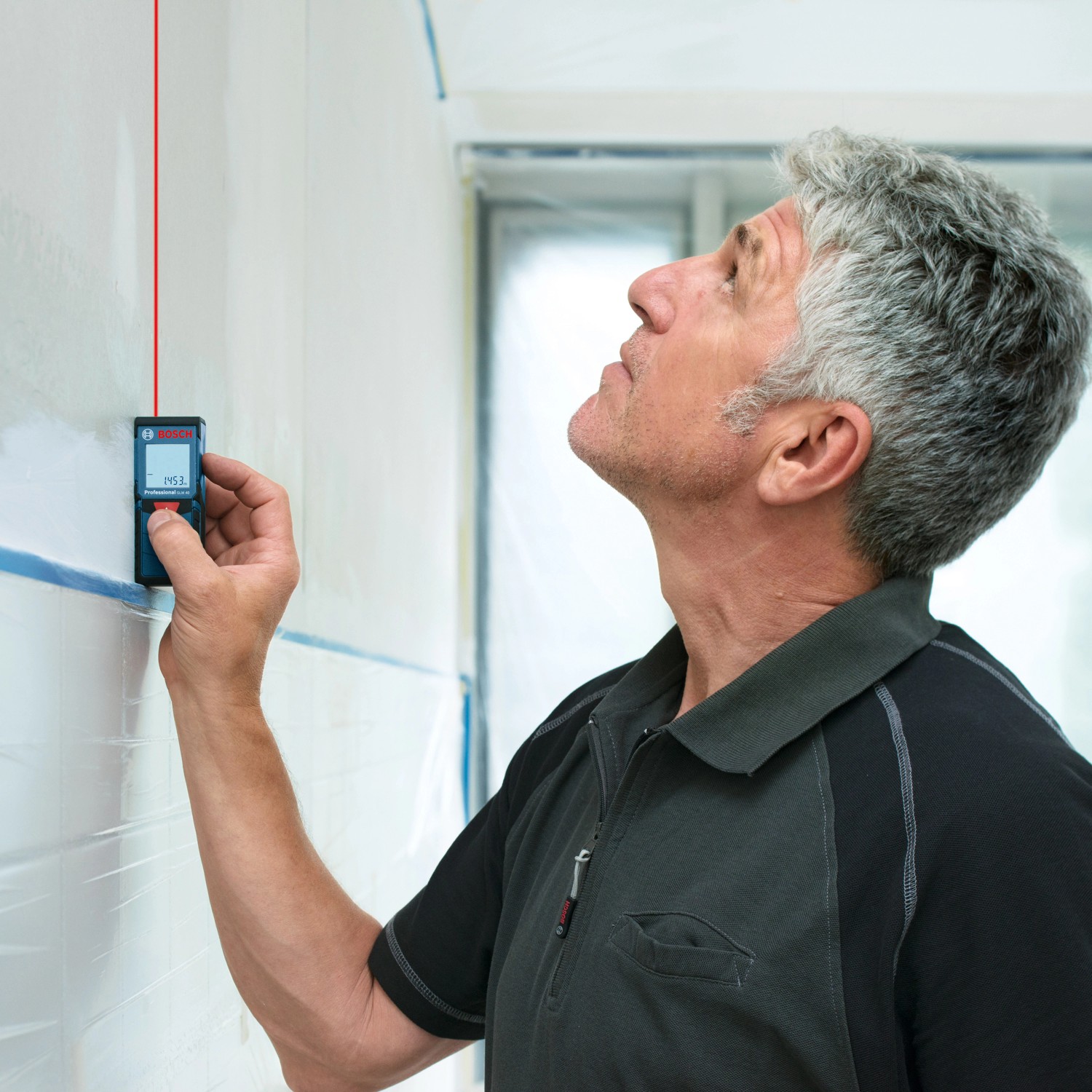 Handwerker misst mit Bosch Professional Laser-Entfernungsmesser GLM 40 digital eine Wand.