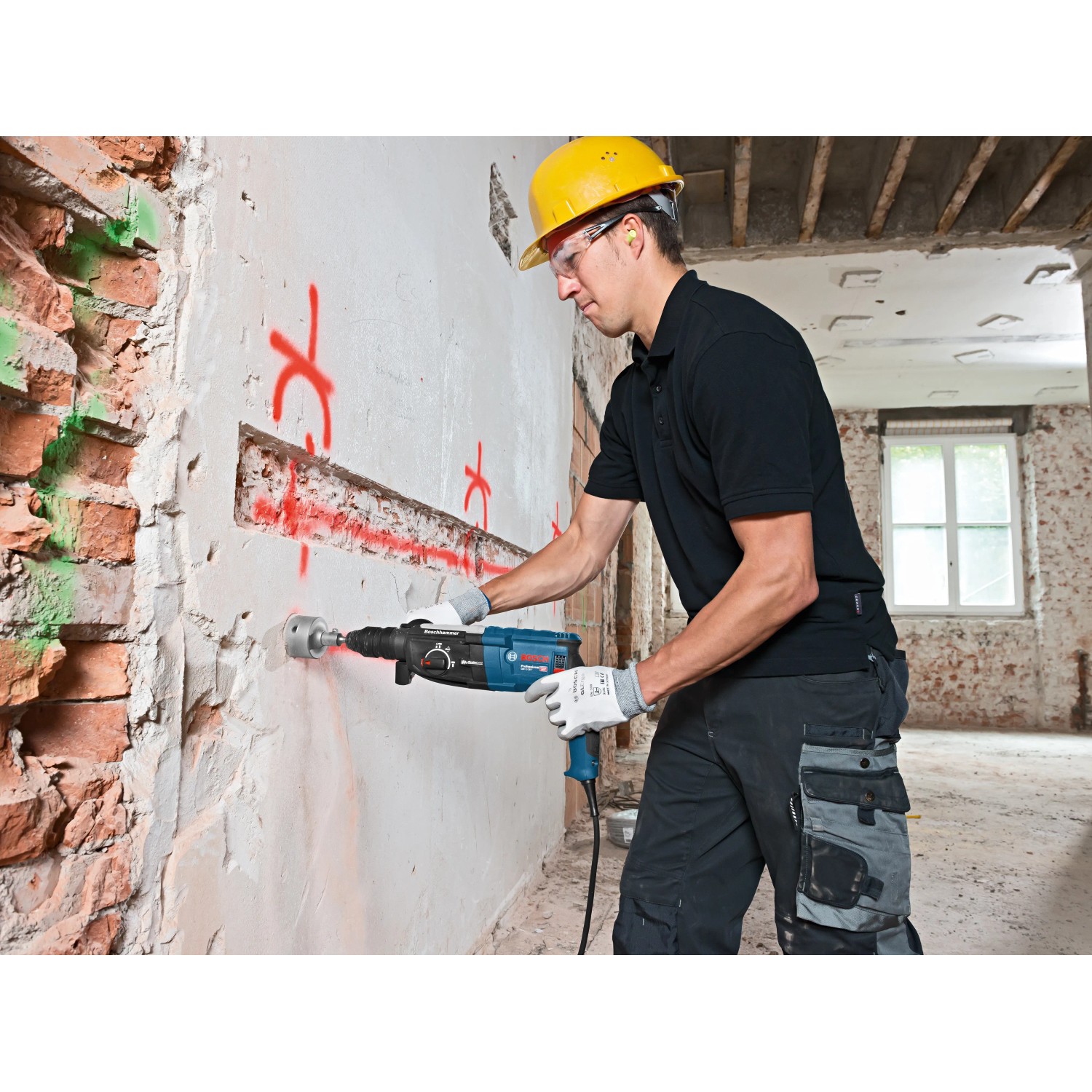 Mann bohrt mit Bosch Professional Bohrhammer GBH 2-28 F in Wand. Inkl. Tiefenanschlag und L-Boxx.