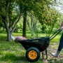 Schwarze Polar Schubkarre Cub Cart mit gelbem Rad und Frau bei der Gartenarbeit.