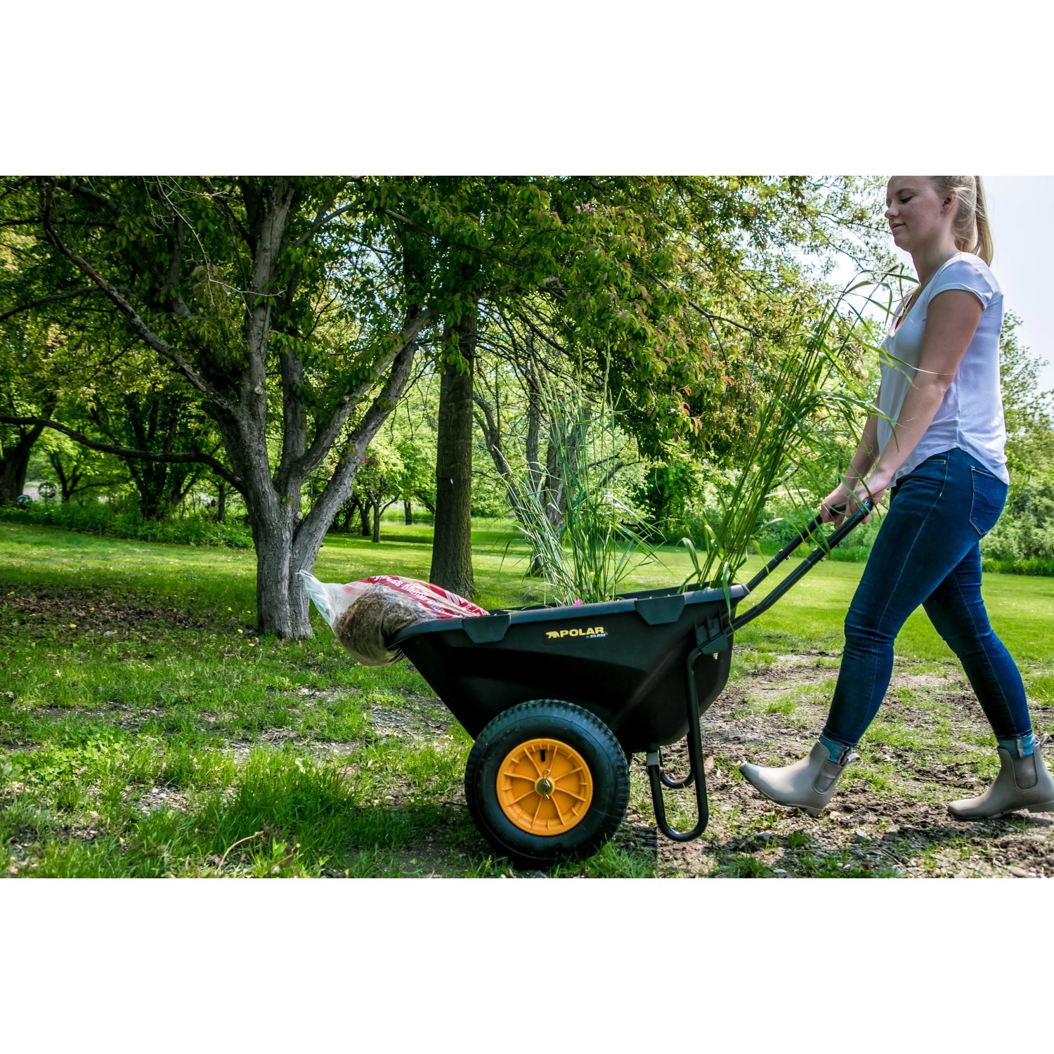 Schwarze Polar Schubkarre Cub Cart mit gelbem Rad und Frau bei der Gartenarbeit.