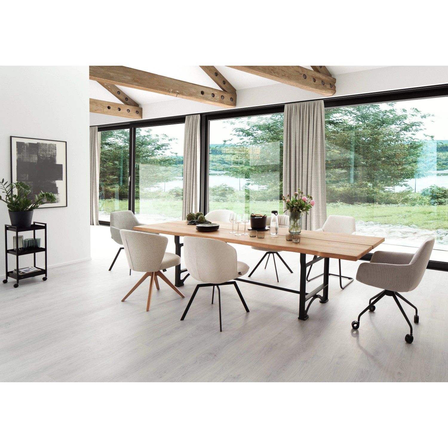 Esstisch mit Stühlen in modernem Esszimmer mit großem Fenster und Blick ins Grüne.