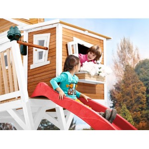 Axi Max Spielhaus mit roter Rutsche, Kinder spielen. Braun-weißes Holzhaus mit Leiter und Sandkasten.