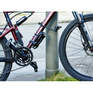 Abbildung eines Fahrrads, das mit einem OBI Faltschloss an einem Pfosten gesichert ist.