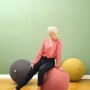 Frau sitzt auf anthrazit Sitting Ball Hocker Felt 150l, weitere Sitzsäcke im Hintergrund.