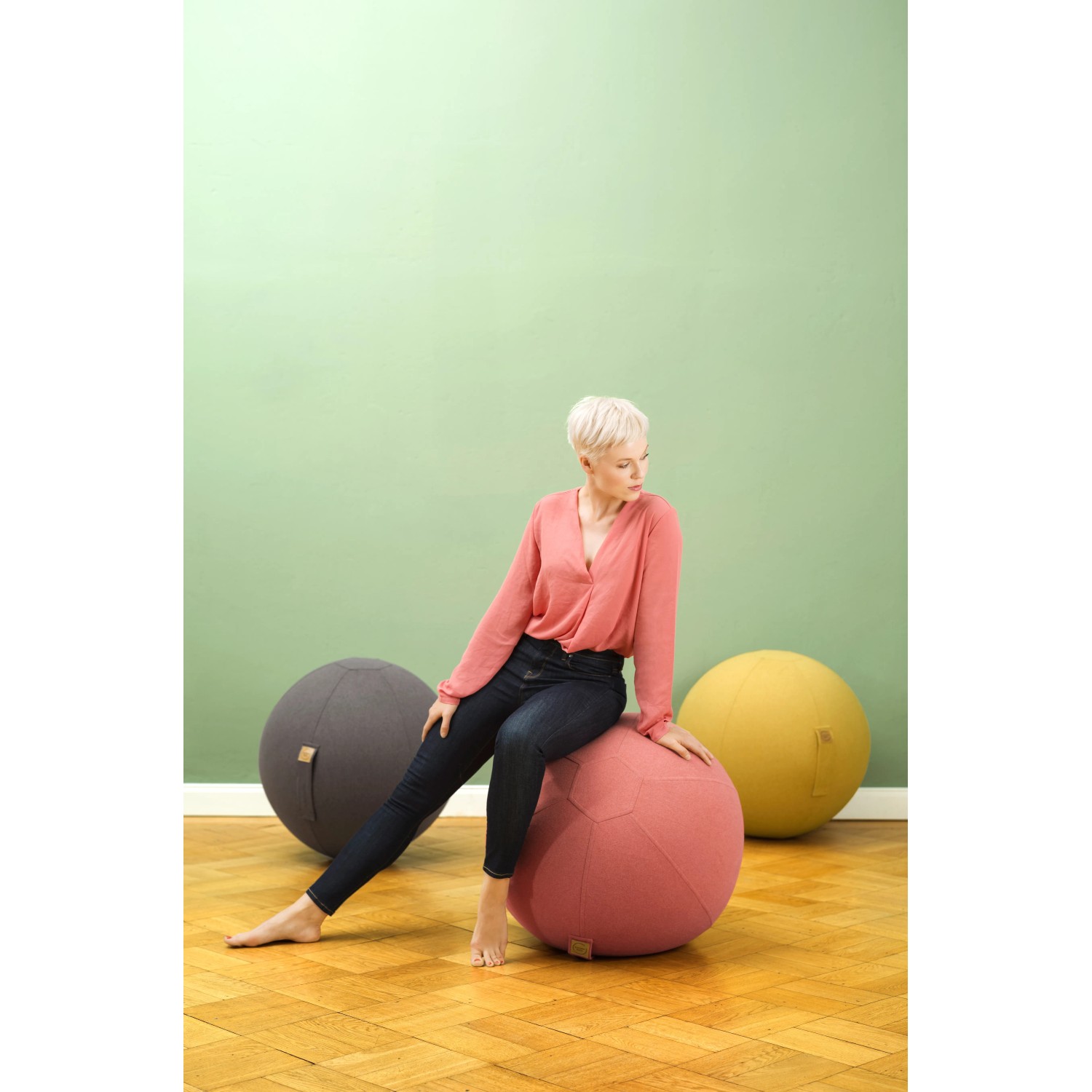 Frau sitzt auf anthrazit Sitting Ball Hocker Felt 150l, weitere Sitzsäcke im Hintergrund.