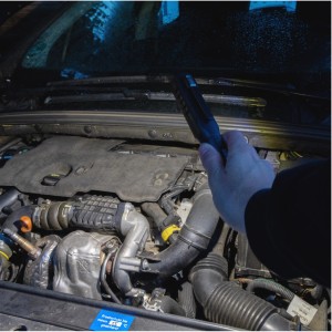 LED Handlampe leuchtet in einem Motorraum. Dimmbare Arbeitsleuchte mit Magnetfuß.