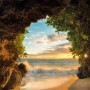 Komar Fototapete Hide Out: Blick aus einer Höhle auf Strand und Meer bei Sonnenuntergang.