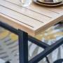 Elati Gartenmöbelset: Tischplatte in Teak-Look mit dunklem Aluminiumgestell. Ein Glas und Schalen stehen auf dem Tisch.