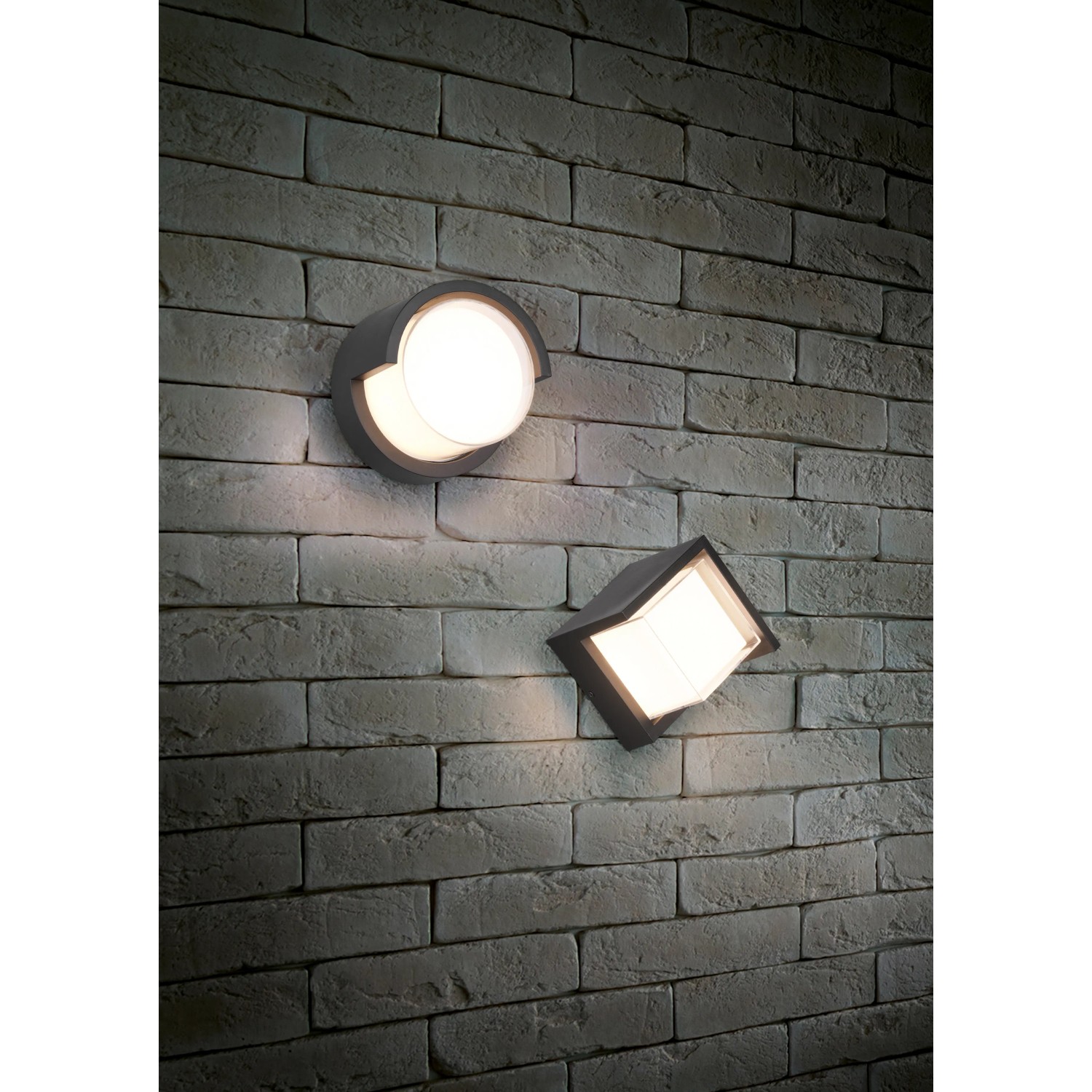 Zwei moderne, mattschwarze Reality LED-Außenwandleuchten Puno an einer Backsteinwand.