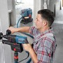 Handwerker bohrt mit Bosch Professional Bohrhammer, Staub wird vom Industriestaubsauger abgesaugt.