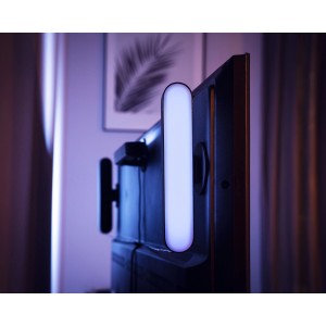 Philips Hue Play LED-Tischleuchte, Schwarz, montiert an einem Fernseher für indirekte Beleuchtung.