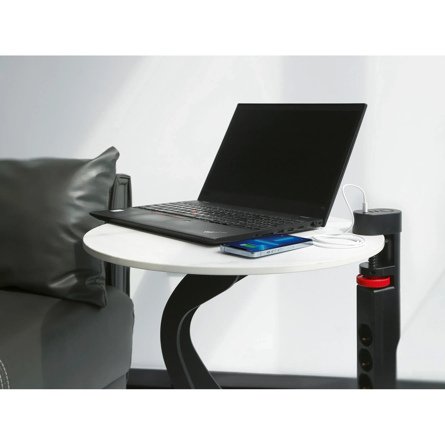 Schwarze 3-fach Steckdosenleiste mit USB-Anschlüssen am Tisch mit Laptop und Smartphone.