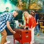 Roter Axi Kühlwagen mit Tischfußball, 65 l, mit spielenden Personen im Garten.