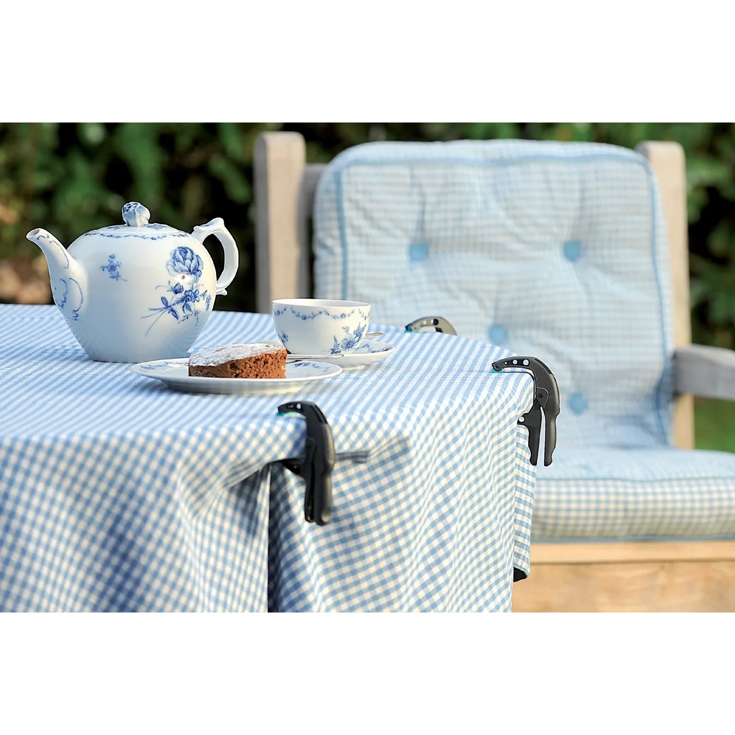 Wolfcraft Ergo-Federzwinge FZH 3 cm im Einsatz auf einem Gartentisch mit blau-weiß karierter Tischdecke.