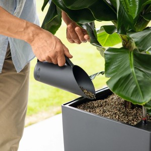 Lechuza Pon Schütte in Schiefergrau beim Einfüllen von Pflanzsubstrat in einen Topf.