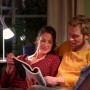 Paar liest bei Licht der Philips Hue White E14 LED-Lampe. Smarte Beleuchtung für gemütliche Stunden.