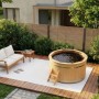 Finntherm Holz-Badefass Bergen (Ø 180 cm) im Garten mit Leiter und Sitzgruppe.