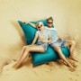 Paar entspannt auf petrolfarbenem Sitting Point Sitzsack Big Foot (380 l) am Strand.