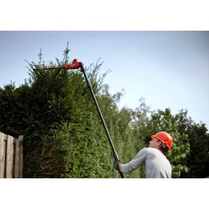 Mann schneidet hohe Hecke mit Skil Akku-Teleskop-Heckenschere 0640CA. Gartengerät mit Verlängerung.