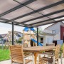 Anthrazitfarbenes Gutta Terrassendach Premium mit Stegplatten und Sitzgruppe im Garten.