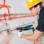 Mann bohrt mit Bosch Professional Bohrhammer GBH 2-28 F in Wand. Inkl. L-Boxx.