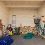 Innenansicht Palmako Ella Holz-Gartenhaus: Unbehandeltes Holz, Flachdach, mit Leiter, Fahrrad und Gartengeräten.
