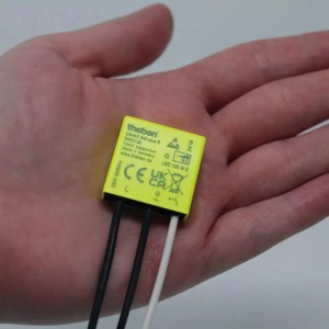 Theben Dimmer DIMAX 540 plus B, gelber UP-Dimmer mit Kabeln in Hand gehalten.