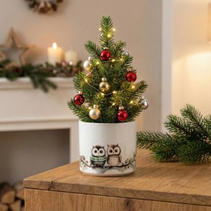 Weißer Keramik Übertopf, 14 cm, mit Eulenmotiv, darin ein festlicher Weihnachtsbaum mit Lichtern & Kugeln.