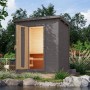 Terragraues Karibu Saunahaus Arvi 1 Set mit geöffneter Tür und Inneneinrichtung im Garten.
