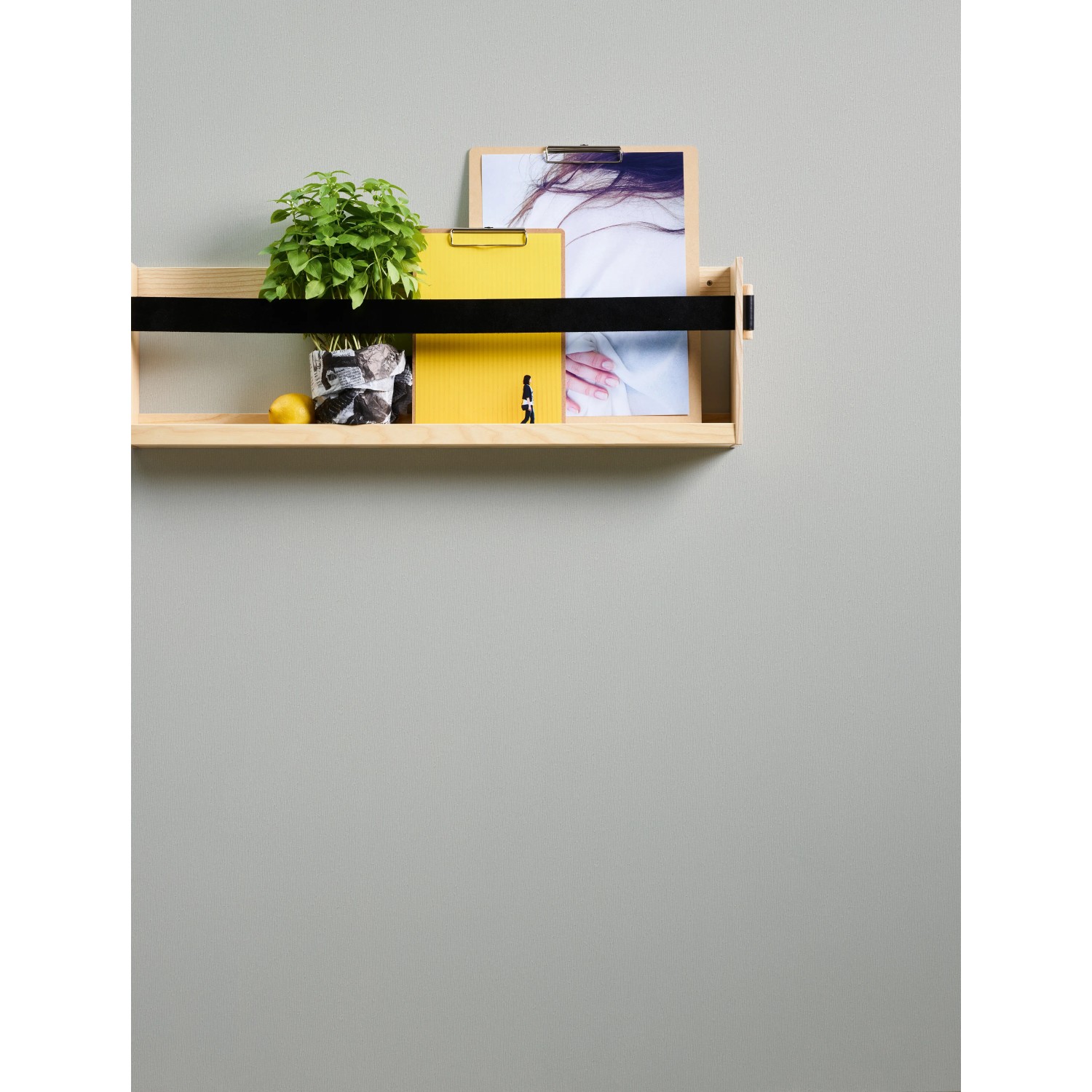Holzregal mit Pflanze, gelbem Ordner und Bild vor grauer Wand. Dekorative Wandgestaltung.