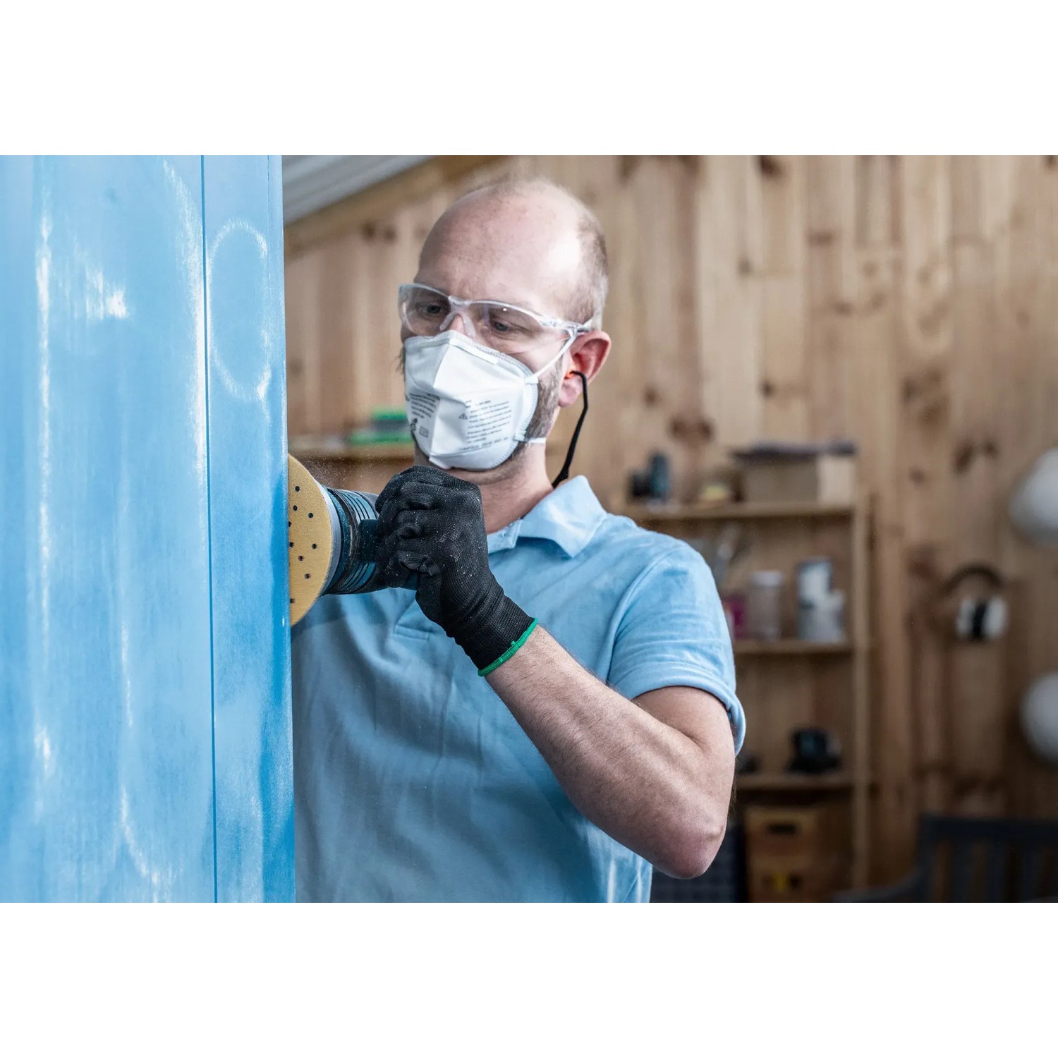 Mann schleift blaue Holzoberfläche mit Bosch Exzenterschleifer und Schleifblatt C470 K60.
