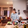 Frau schneidet Gemüse in Küche mit Philips Hue LED. Wohnzimmer im Hintergrund.