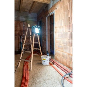 Eglo LED-Baustrahler Avelar (200 W, schwarz-türkis) auf einer Leiter in einem Rohbau.
