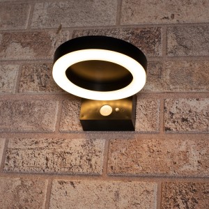 Schwarze Solar-Wandleuchte Marseille mit Sensor an Backsteinwand. Außenleuchte mit LED-Ring.