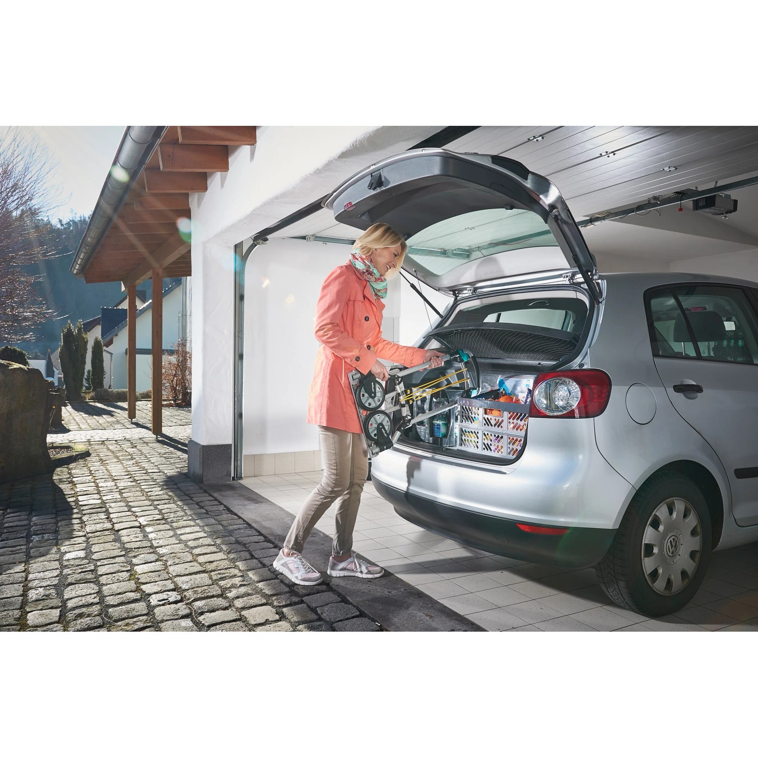 Frau lädt klappbare wolfcraft Sackkarre TS 600 in den Kofferraum eines Autos.