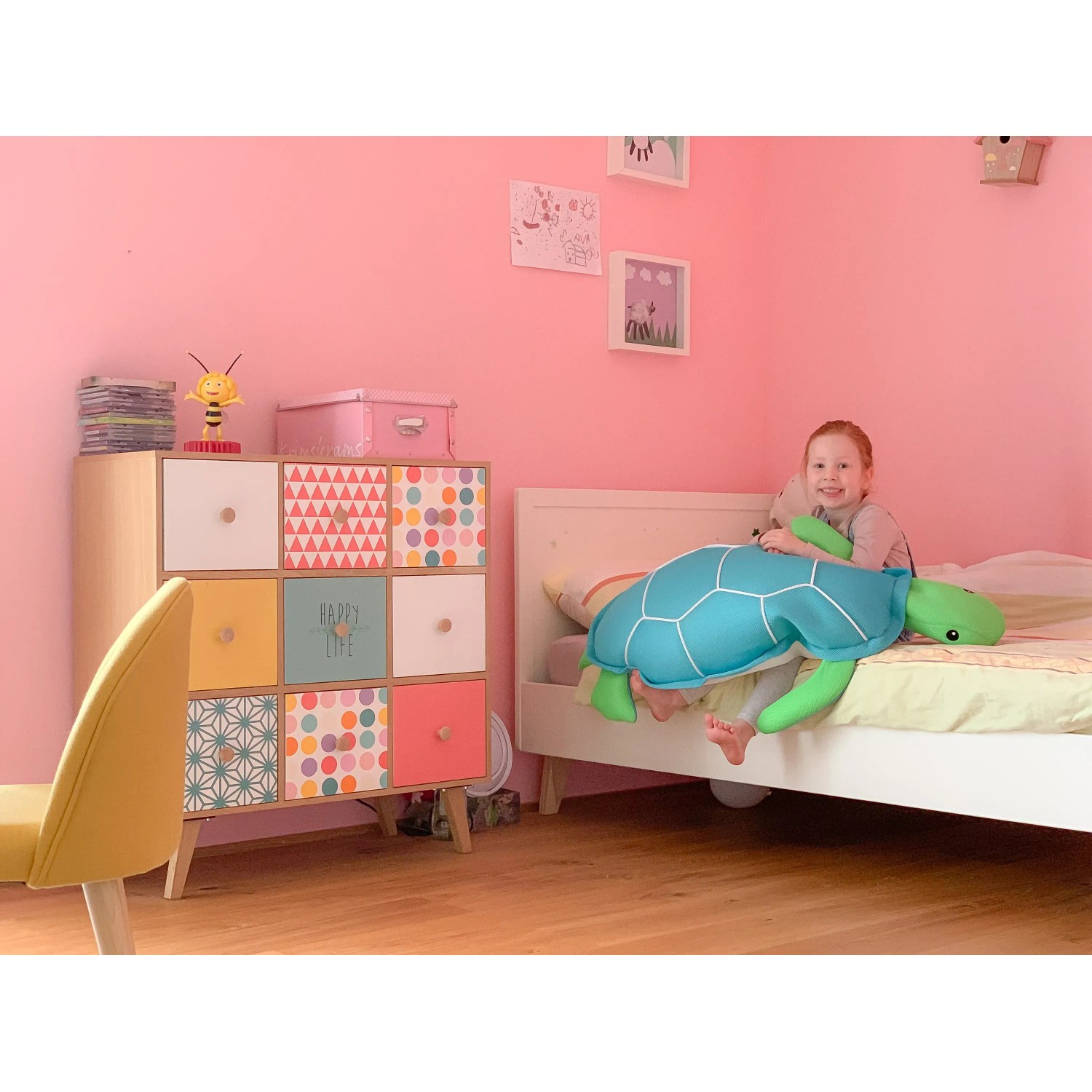 Mädchen sitzt auf Bett mit Westmann Pool Buddy Schildkröte Blau, einem blauen Schwimmtier.