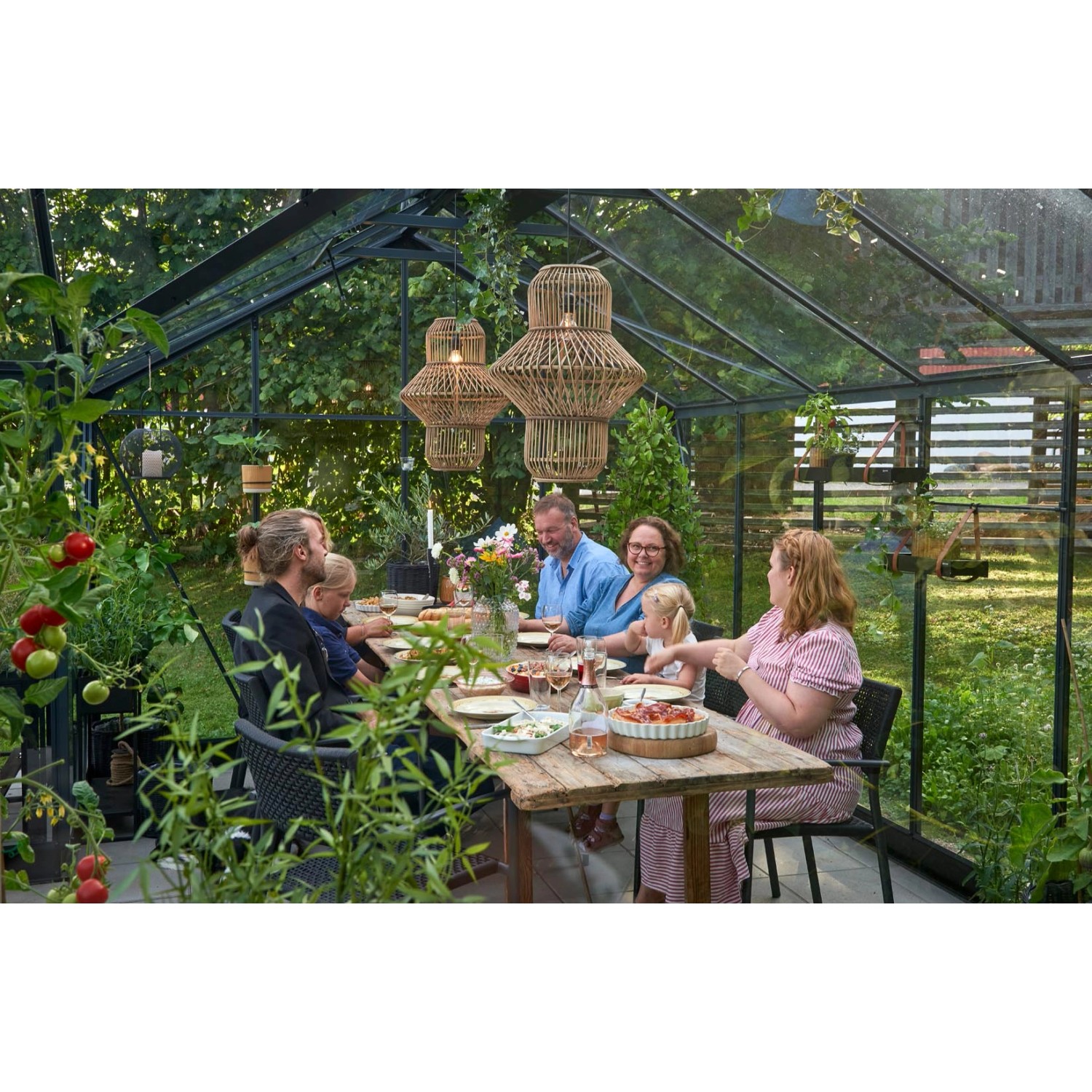 Familie beim Essen im Juliana Gewächshaus Orangerie 21 Schwarz-Anthrazit. Gemütliche Atmosphäre im Garten.